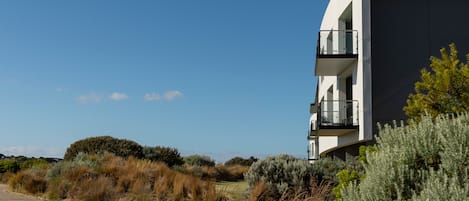 A modern building with a curved facade, a balcony, and a pathway leading to it.