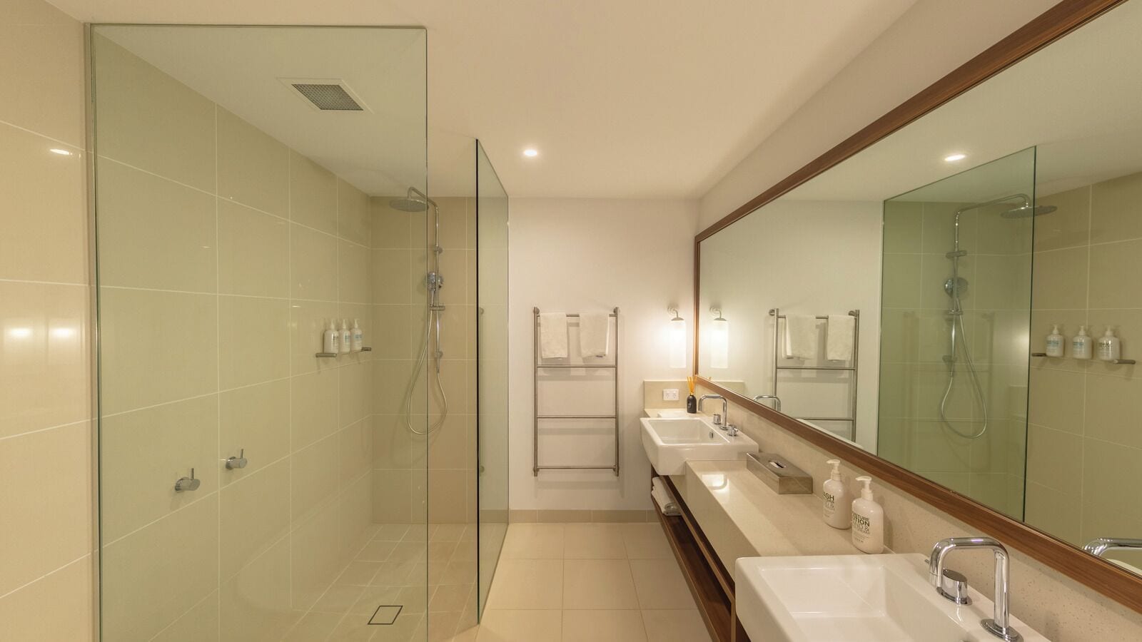 A modern bathroom with a glass-enclosed shower, a vanity with a large mirror, and a walk-in shower.