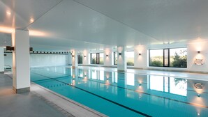 A large indoor swimming pool with clear blue water, surrounded by white walls and large windows. - The Sands Torquay (Torquay)