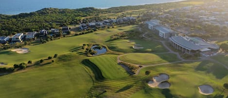 Een golfbaan met bunkers, een clubhuis en woongebouwen.