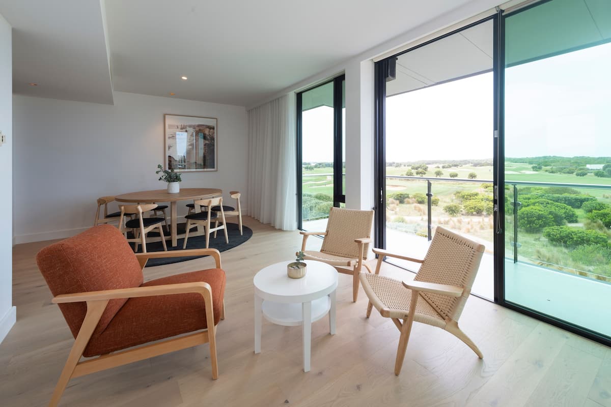 Ein modernes Wohnzimmer mit Essbereich, großen Fenstern und Blick auf einen Golfplatz.