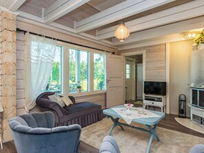 Ein gemütliches Wohnzimmer mit einer Couch, Sesseln, einem Couchtisch und einem Fernseher.