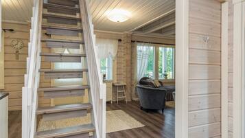 Un intérieur en bois comprenant un escalier, un coin repas et un salon avec un canapé et une table.