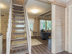 A wooden interior with a staircase, a dining area, and a living room with a sofa and a table. - Haapaniemi by Interhome (Punkaharju)