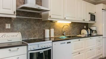 Een koelkast, een magnetron, een vaatwasser, kookgerei, borden en bestek