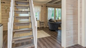 Ein Holzinnenraum mit einer Treppe, einer Uhr, einem Fenster mit Vorhängen und einem Sofa.