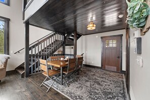 A dining area with a wooden table and chairs, a staircase, and a door. - Whiskey Hills At Terry Peak (North Lawrence)