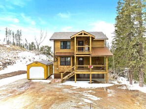 A two-story wooden cabin with a balcony, a garage, and a covered porch. - Whiskey Hills At Terry Peak (North Lawrence)