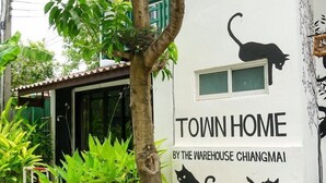 Ein Gebäude mit weißer Fassade und einem Wandgemälde von schwarzen Katzen.