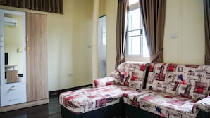 Ein Zimmer mit einer Couch, einem Kleiderschrank und einem Fenster mit Vorhängen.