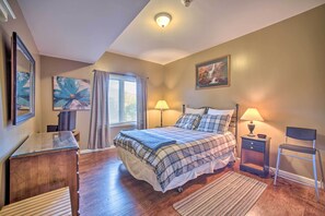 Une chambre à coucher avec un lit, des tables de chevet, une chaise, un bureau et une fenêtre avec des rideaux.