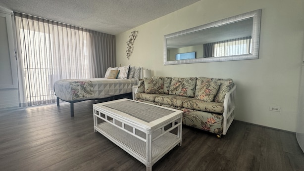 A hotel room with a bed, a sofa, a coffee table, and a large mirror.
