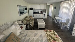 A compact living space with a kitchenette, a sofa, a dining table, and a chair.