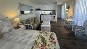 A compact living space with a kitchenette, a dining area, and a bedroom.
