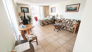 Amplia sala de estar con sofá, mesa de comedor y balcón con una silla roja.