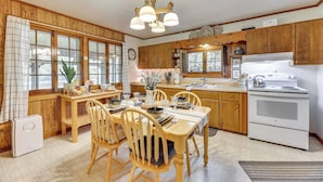 Une cuisine avec des meubles de rangement en bois, une cuisinière blanche et une table à manger avec des chaises.