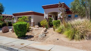 Zona residencial con dos casas de estilo mediterráneo, rodeada de jardines ajardinados y vegetación adaptada al desierto.