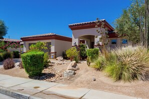 Zona residencial con dos casas de estilo mediterráneo, rodeada de jardines ajardinados y vegetación adaptada al desierto.