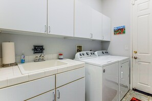 A laundry area with a sink, two washing machines, and a cabinet.