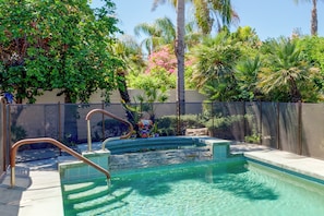 Una piscina con agua cristalina, rodeada por una cerca y abundante vegetación.