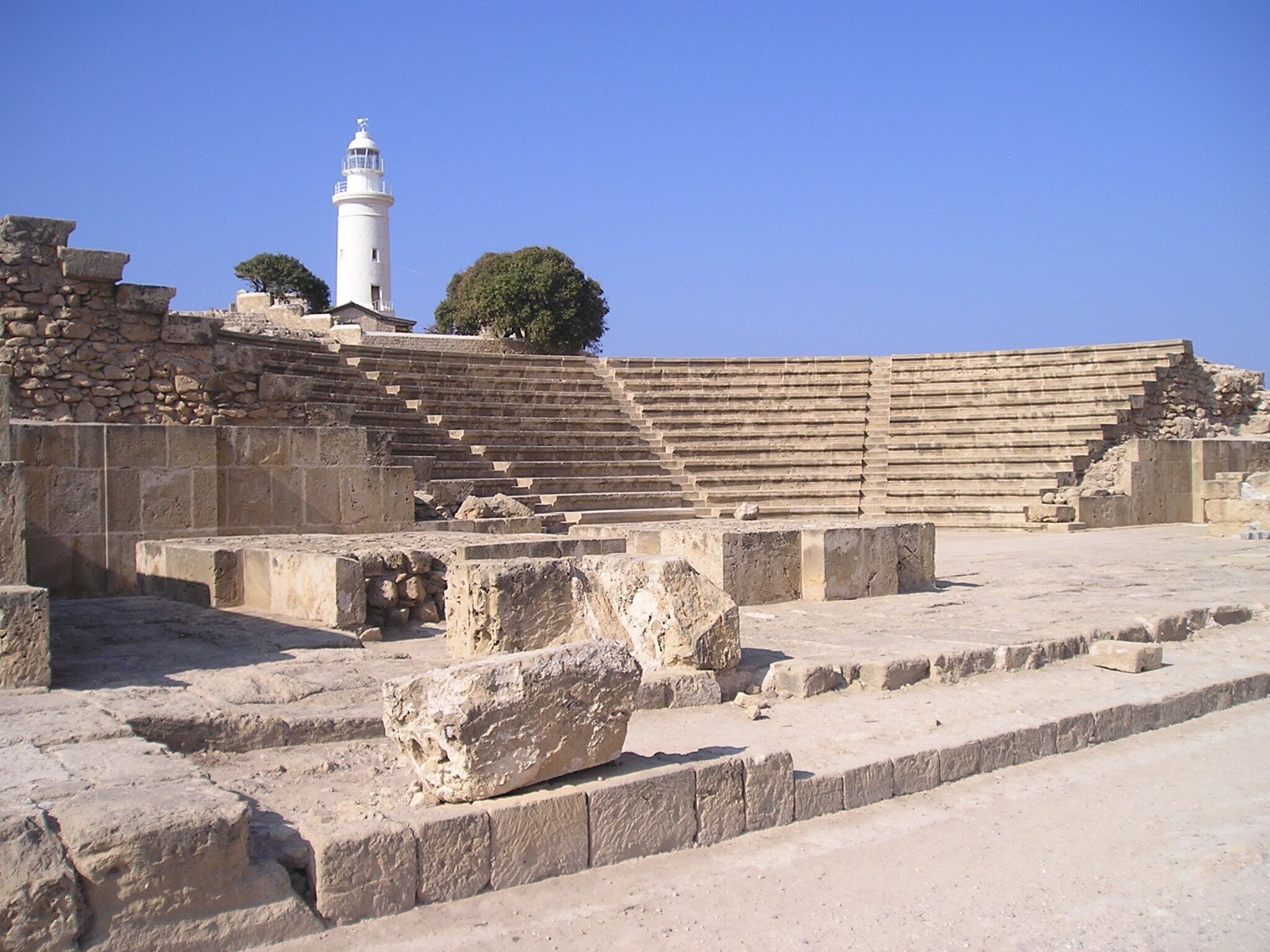 Ancient ruins with stone steps and a lighthouse.