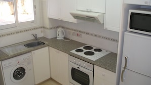 A compact kitchen with a built-in washer, a stove, and a microwave.