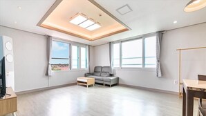 Un salon spacieux comprenant un canapé, une table basse, un téléviseur et un coin repas.