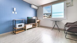 Un salon moderne équipé d’un téléviseur, d’un four à micro-ondes et d’une petite table.