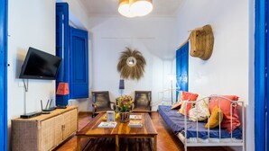 A room with a bed, a table with books, a TV, and a wall-mounted lamp. - El Patio Andaluz – House with Pool for Groups (13 Guests) in Vélez-Málaga (Vélez Malaga)