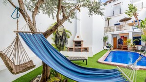 A poolside area with a hammock, a barbecue, and a small table. - El Patio Andaluz – House with Pool for Groups (13 Guests) in Vélez-Málaga (Vélez Malaga)