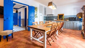 A kitchen with a wooden table and chairs, blue doors, and a tiled floor. - El Patio Andaluz – House with Pool for Groups (13 Guests) in Vélez-Málaga (Vélez Malaga)