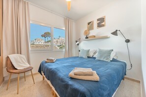 Una camera da letto con un letto, una sedia, una finestra con vista e una lampada da scrivania.
