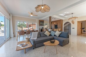 A spacious living room with a grey sofa, wooden coffee table, and a dining area with chairs and a table.
