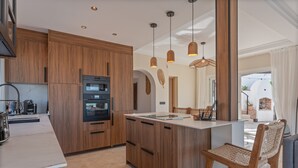 A modern kitchen with wooden cabinets, a built-in oven, and pendant lighting. - Villa 'Casa Leo Holiday' with Sea View, Wi-Fi and Air Conditioning (Mijas Costa)