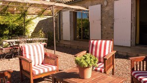 An outdoor patio with wooden furniture, a potted plant, and a stone wall. - Sunny Escape to Serenity (Fraissé-Des-Corbieres)