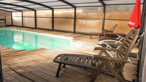 An indoor pool area with a wooden deck, lounge chairs, and a red umbrella. - Sunny Escape to Serenity (Fraissé-Des-Corbieres)