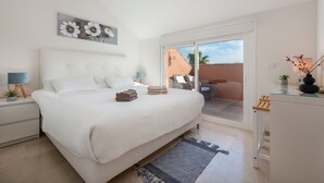 A bedroom with a bed, bedside tables, a nightstand, a window with a view, and a ceiling light. - Apartment 'La Fragata Estepona 3b 2b' with Sea View, Wi-Fi and Air Conditioning (Estepona)