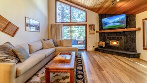 Ein gemütliches Wohnzimmer mit Kamin aus Stein, einem großen Flachbildfernseher, einer Couch und einem Couchtisch.