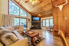 Un salón espacioso con chimenea de piedra, un televisor grande y techo de madera.