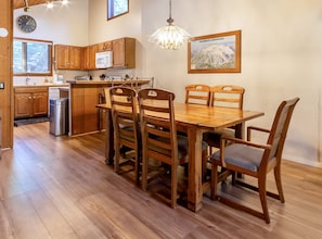 Una cocina con armarios de madera, un microondas, un fregadero y una zona de comedor con mesa y sillas de madera.