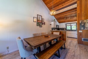 Ein Essbereich mit Holztisch und Bänken, einer Kandelaber und gerahmten Bildern an der Wand.