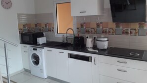 A modern kitchen with a washing machine, microwave, toaster, sink, and a TV mounted above the counter. - the creolia rue motais in narbonne le tampon  (Le Tampon)