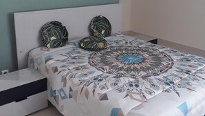 A bedroom with a bed, a nightstand, a white lamp, and a teal accent wall. - the creolia rue motais in narbonne le tampon  (Le Tampon)