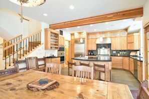 Una cocina amplia con armarios de madera, una isla central y un comedor con sillas de madera.