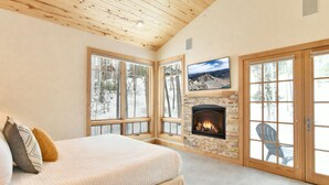 A bedroom with a large bed, a fireplace, and large windows. - Summit Rose Escape • Theater Rm • Gourmet Kitchen (Frisco)