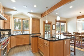 Una cocina amplia con armarios de madera, una isla grande y un comedor con sillas y mesa.