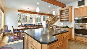 A spacious kitchen with a large island, wooden cabinets, and a stone fireplace. - Summit Rose Escape • Theater Rm • Gourmet Kitchen (Frisco)