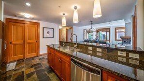 A modern kitchen with granite countertops, stainless steel appliances, and wooden cabinets. - Capitol Peak Lodge 3306 (Snowmass)