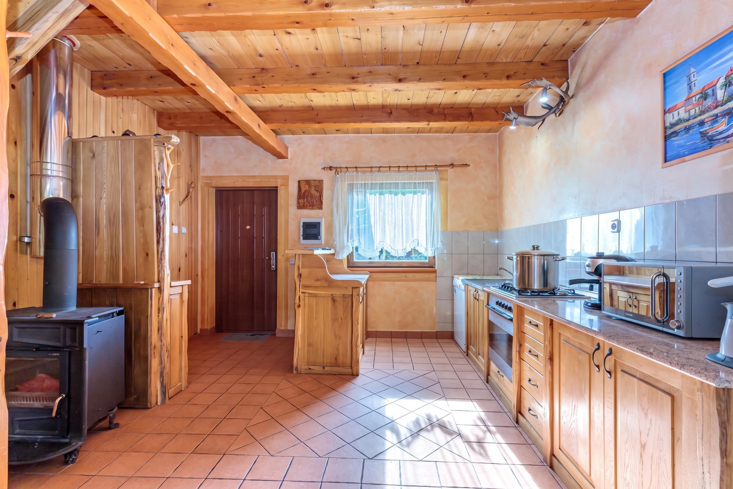 Un interior de madera con cocina, que incluye una estufa, armarios y una ventana con cortinas.