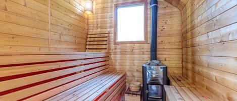 A sauna with wooden benches and a sauna heater.
